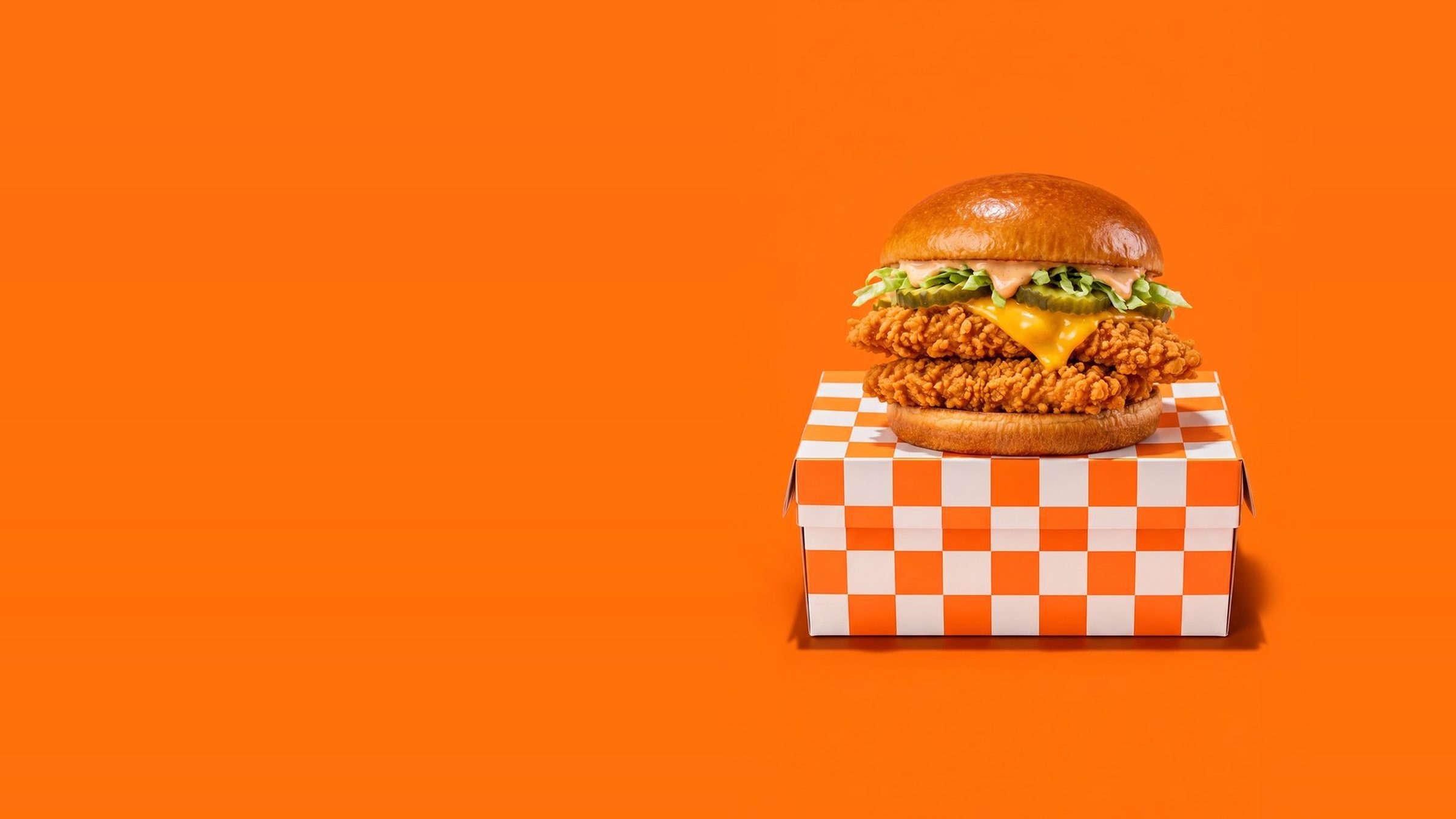 Seau de tenders de poulet frit et wings épicées devant un damier orange et noir