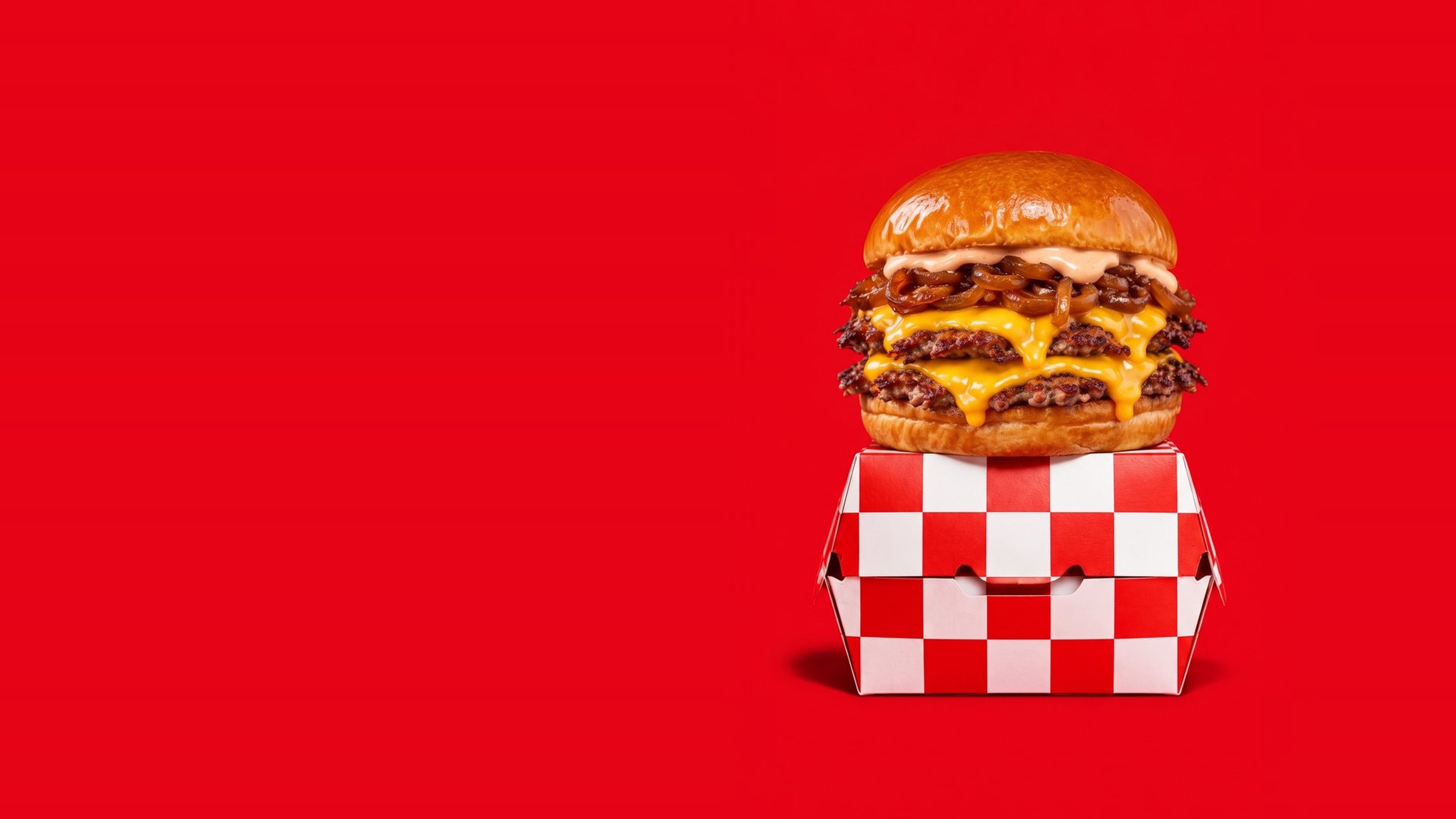 Smash burger double cheddar et cornet de frites devant un damier rouge et blanc